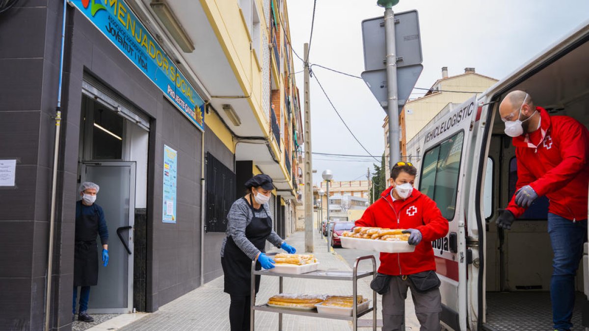 Dos membres de Creu Roja recullen aliments per portar-los al pavelló del Serrallo.