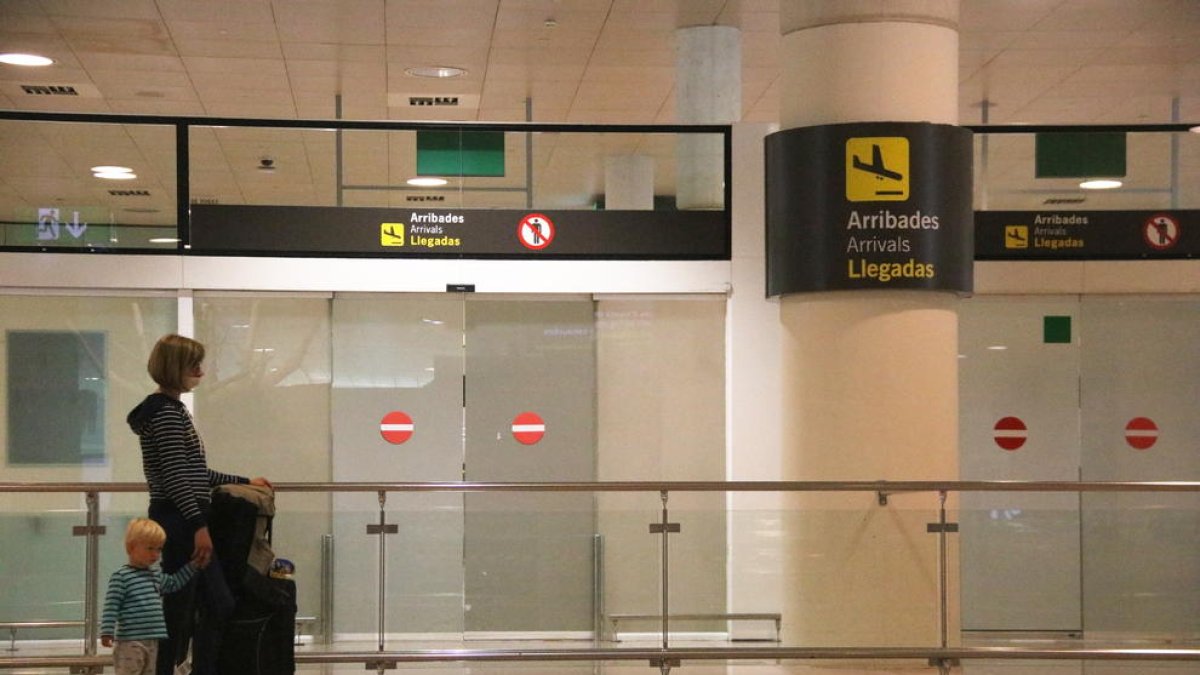 Pla general d'una passatgera esperant davant la zona d'arribades a l'aeroport de Barcelona.