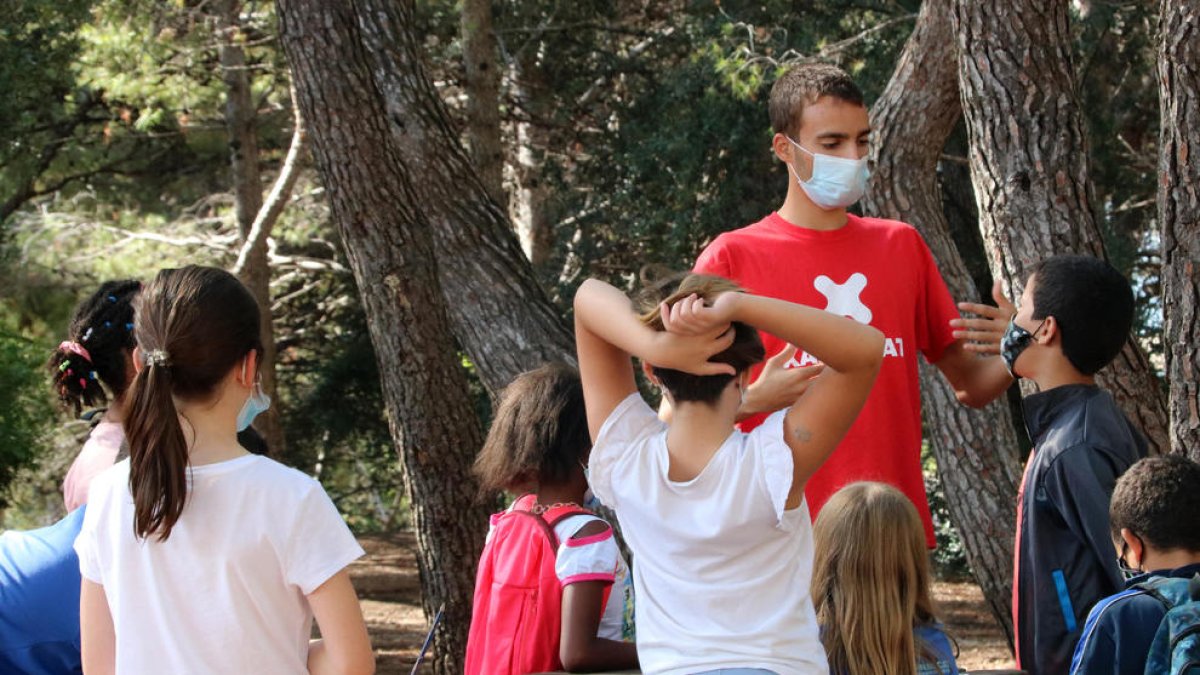 Un monitor de ocio haciendo una actividad con niños, todos con mascarillas.