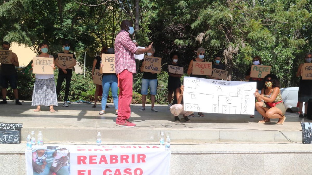 Ibrahima Sylla conduint una reproducció de l'operació policia al pis om vivia el seu germà, darrere un cartell que reclama la reobertura del cas de la mort del manter.