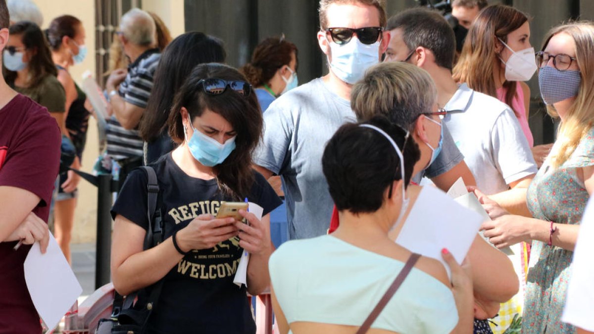 Plano abierto de numerosos ciudadanos haciendo cola con mascarilla para acceder a hacerse una prueba PCR en Vilafranca del Penedès.