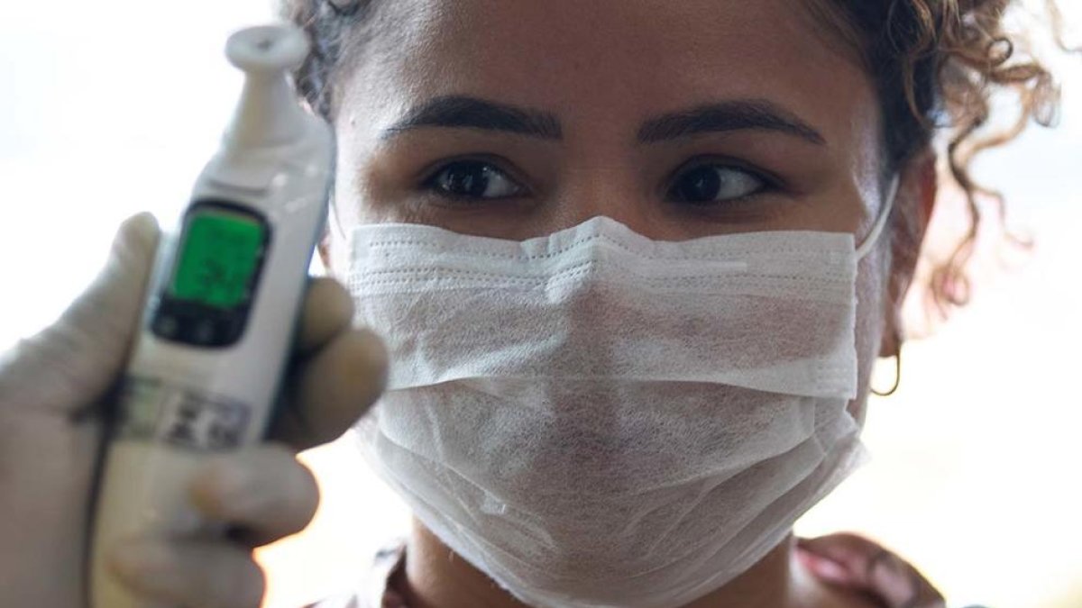 Personal sanitario toman la temperatura a una paciente.