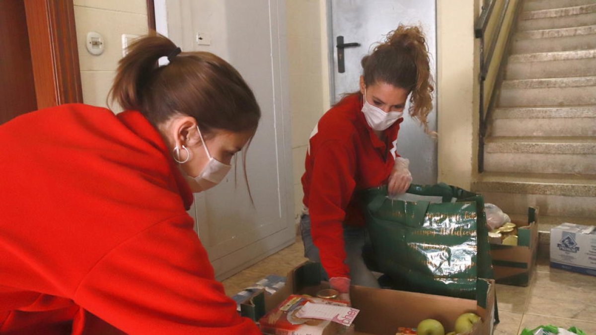 Des tècniques de Creu Roja Tarragona posant el menjar en bosses de plàstic des del replà de casa del beneficiari, pero no entrar-hi com a mesura preventiva per la covid-19.