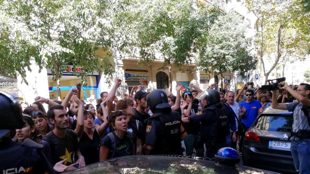 La policia espanyola envoltant la seu de la CUP, mentre simpatitzants criden en contra de l'actuació i en favor de l'1-O, el 20 de setembre de 2017.