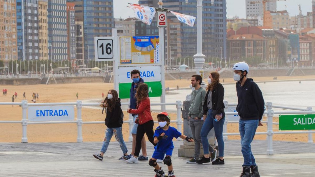 Un grup de persones passegen pel passeig marítim de la platja de Sant Lorenzo de Gijón