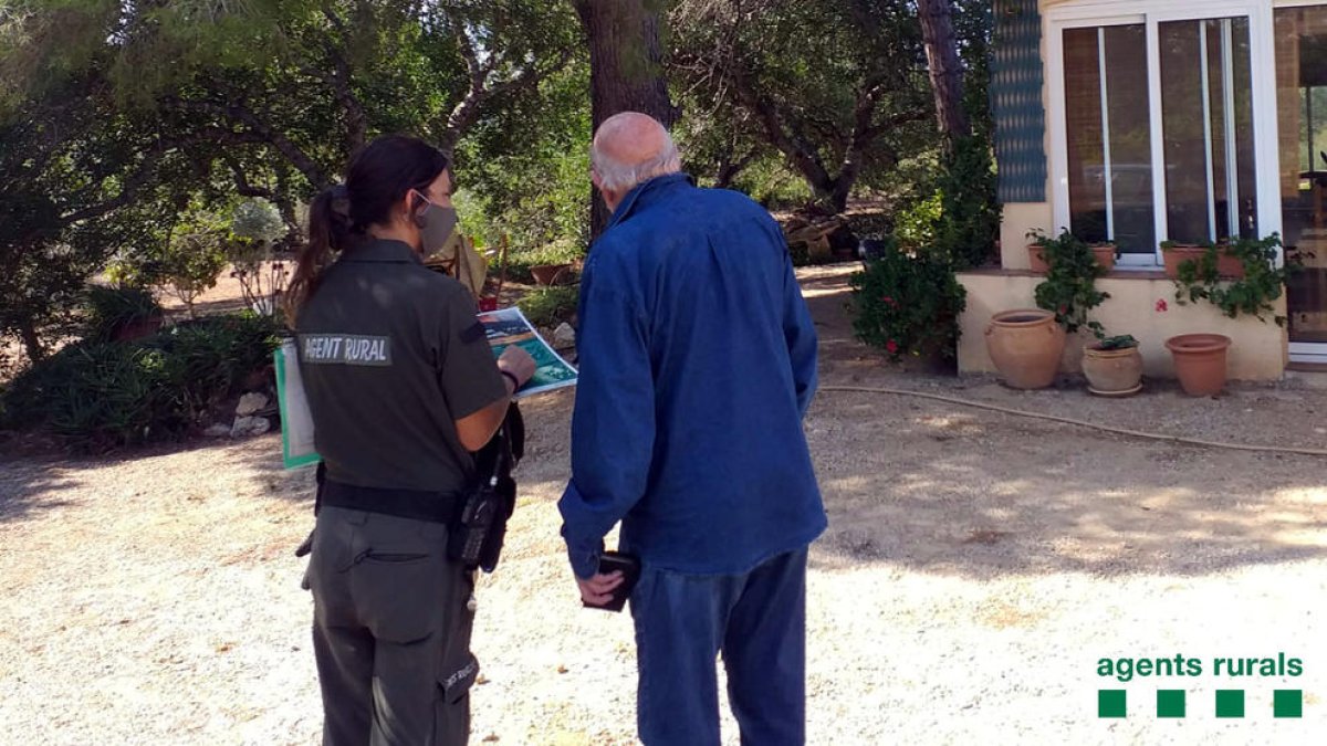 Una Agente Rural informante un propietario del Perelló sobre los perímetros de autoprotección en caso de incendio forestal.