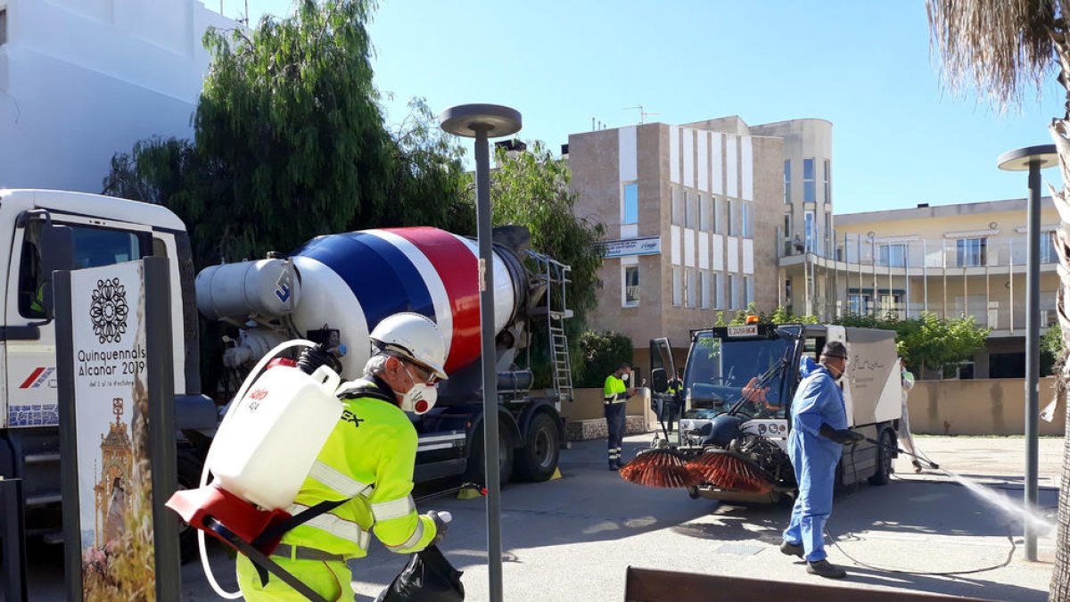 Els operaris municipals i del camió-formigonera, facilitat per Cemex, durant les tasques de desinfecció als carrers d'Alcanar