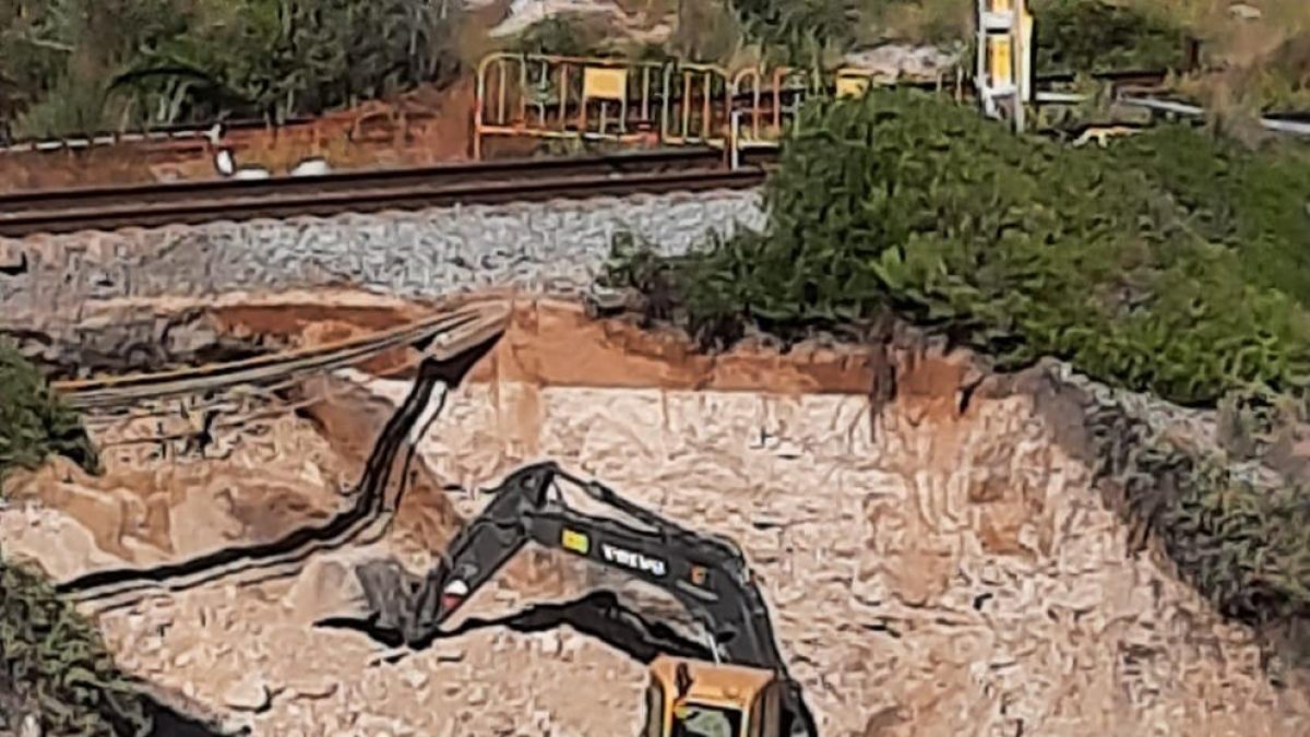 Una excavadora trabaja para reparar un boquete en el tramo Vilanova-Sitges de la línea de Rodalies de Renfe R2 sur.