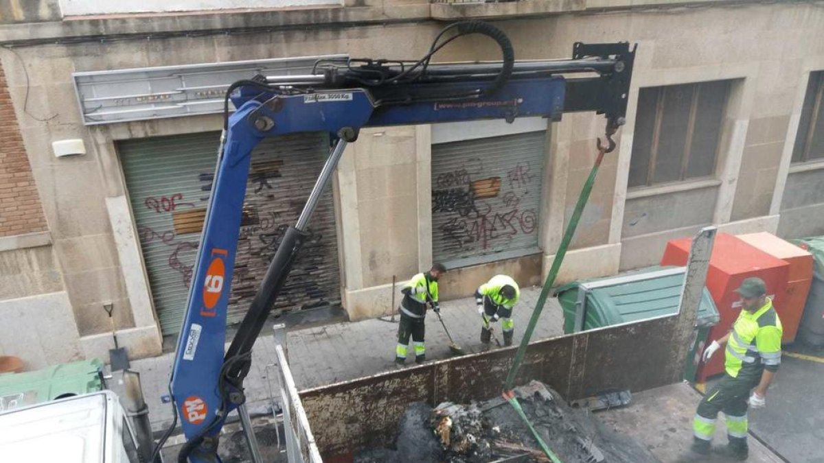 Operarios de limpieza retirando los contenedores quemados en la calle de la Selva del Camp.