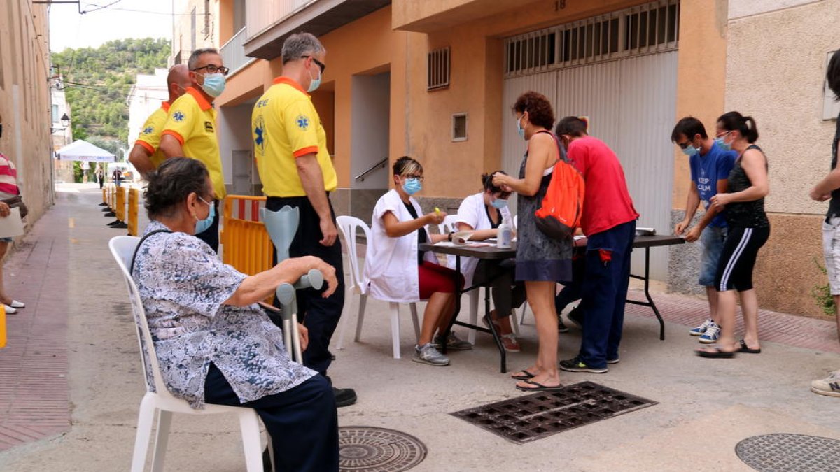 Plano abierto de varios vecinos de Benifallet dirigiéndose a una mesa de identificación con el fin de realizarse una prueba PCR.