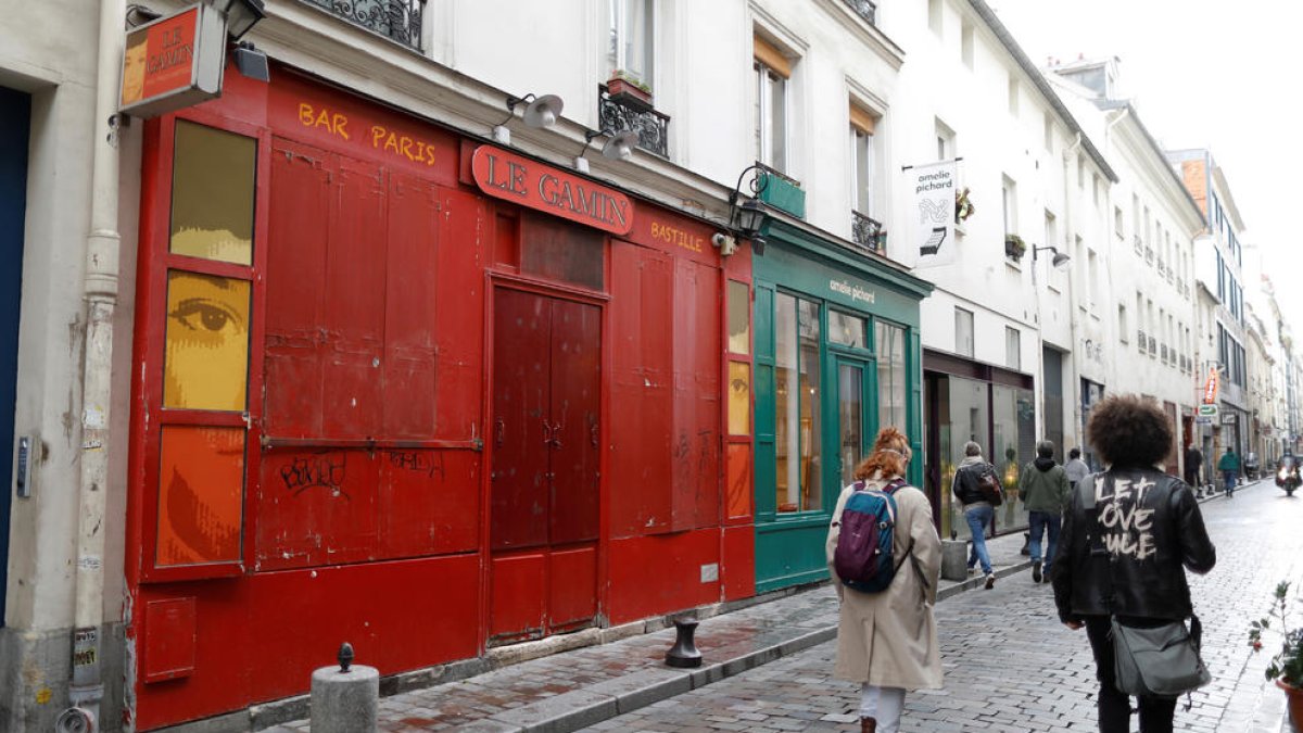 Diverses persones caminen davant d'un bar tancat per les restriccions de la covid-19 a París.