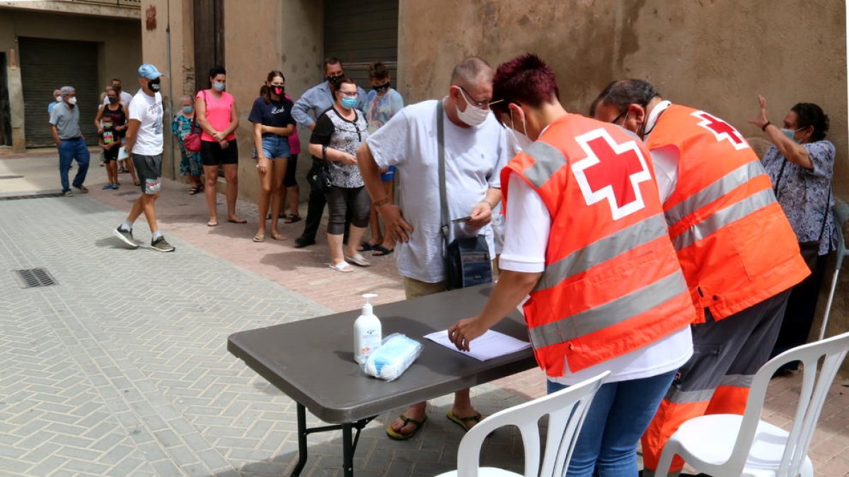 Pla obert de veïns de Benifallet fent cua davant un taulell d'inscripció per fer-se una prova PCR.