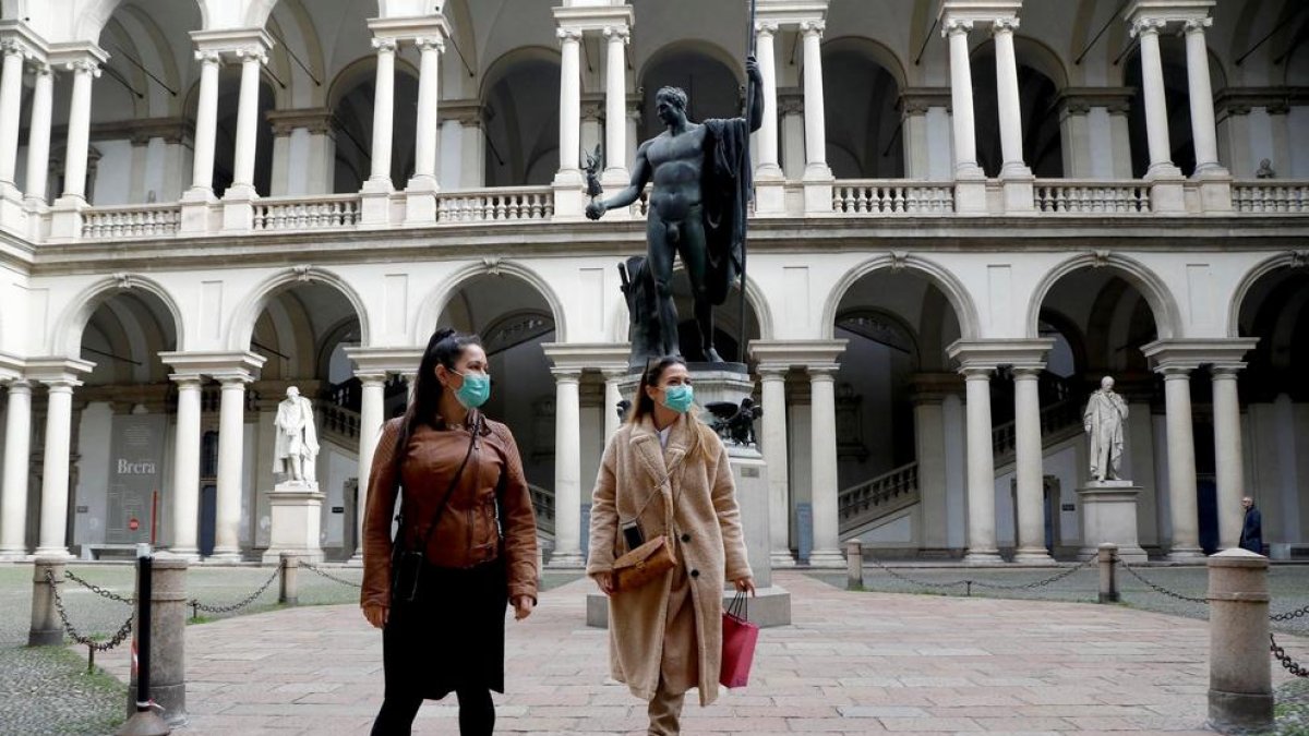 Dos turistas con mascarillas mientras visitan el claustro del Palazzo di Brera de Milán, donde ya se han confirmado diversos infectados.