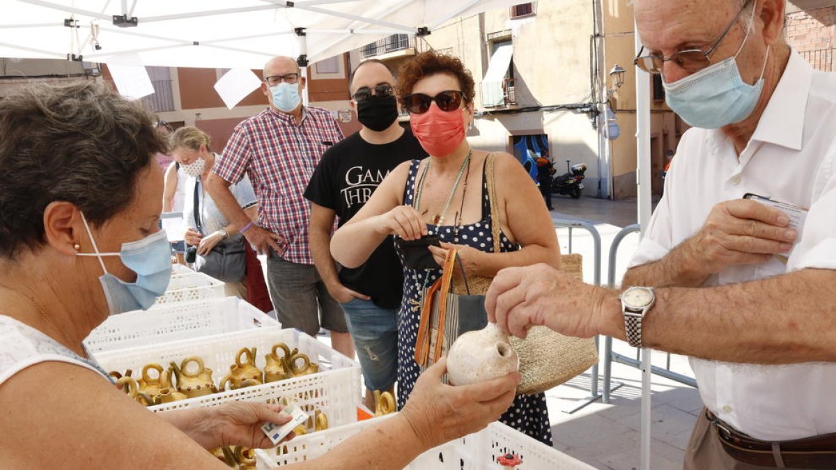 Un anciano comprando un botijo con agua bendecida de Sant Magí, en un espacio habilitado en la Part Alta.