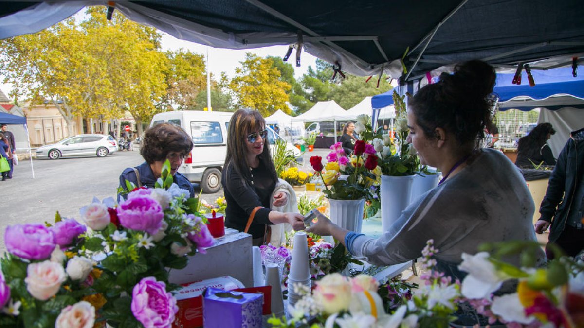 Imagen de clientes comprando flores a un puesto del Mercado de flores en el cementerio de Tarragona el día de Todos los Santos de 2018.