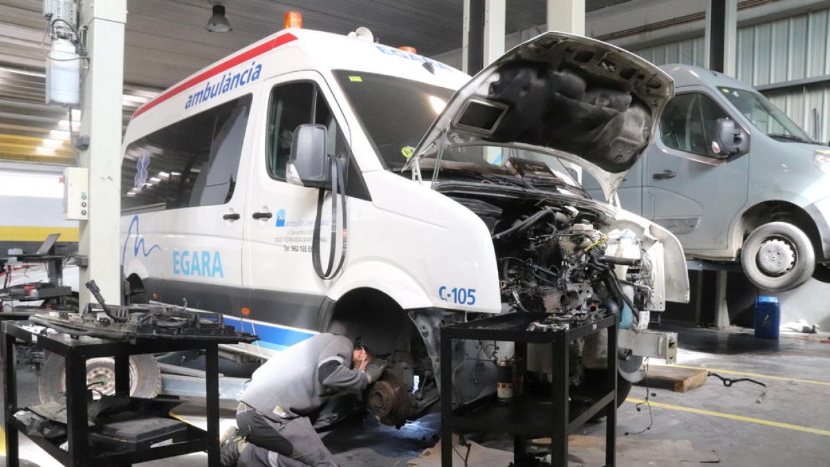 Pla mitjà d'un mecànic en un taller que només repara vehicles de serveis essencials