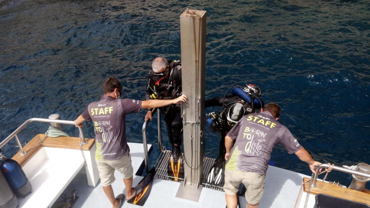 Dos submarinistas subiendo al barco del centro de buceo después de hacer una inmersión en las islas Medes.