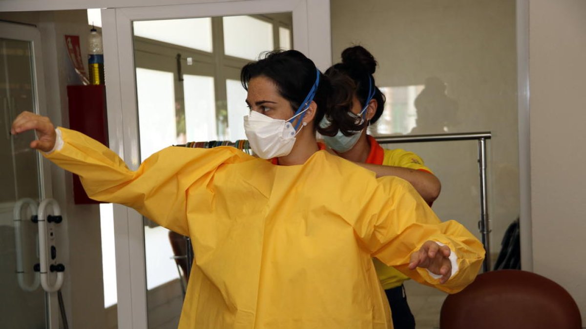 Dos sanitarias equipándose con EPI's para hacer pruebas PCR en Albesa.