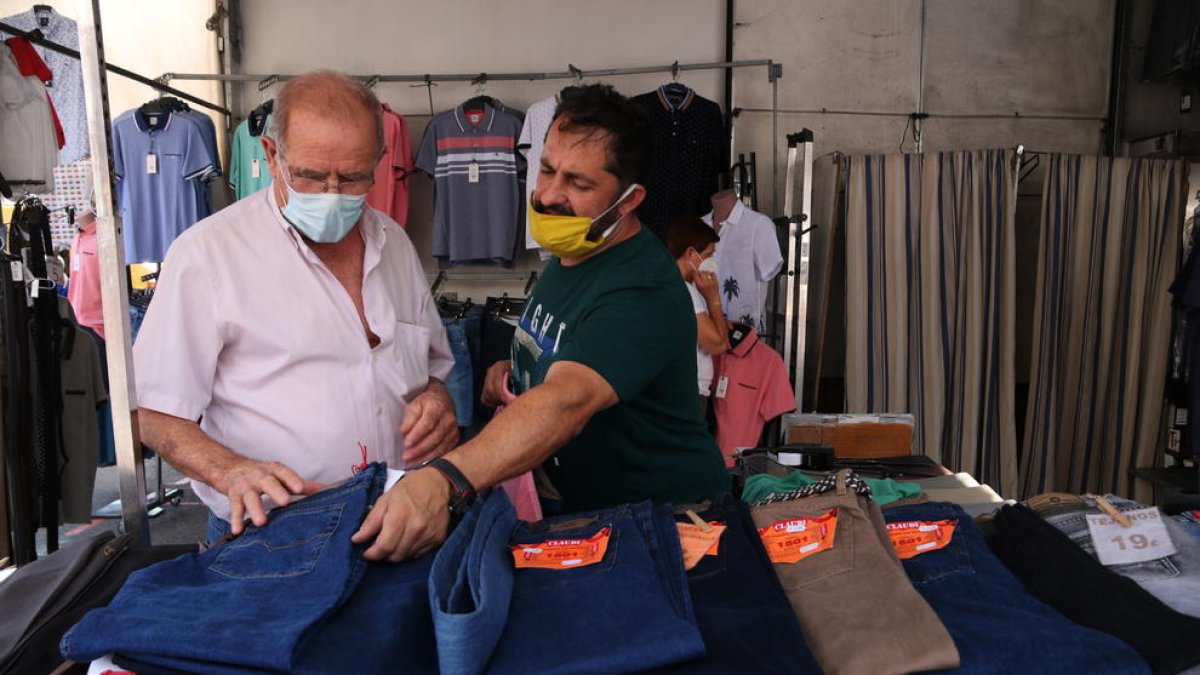 Un paradista i un client comprant en una de les parades de roba del mercat de Bonavista que ha reobert després de tres mesos d'inactivitat.