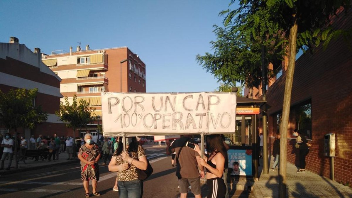 Dos personas sostienen una pancarta reivindicativa y, en el fondo, parte de la gente que se manifestó.