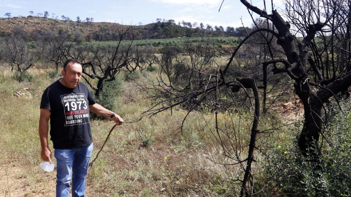 El campesino de Bovera Julio Cabre mostrando un tubo de riego quemado por el incendio de hace un año.