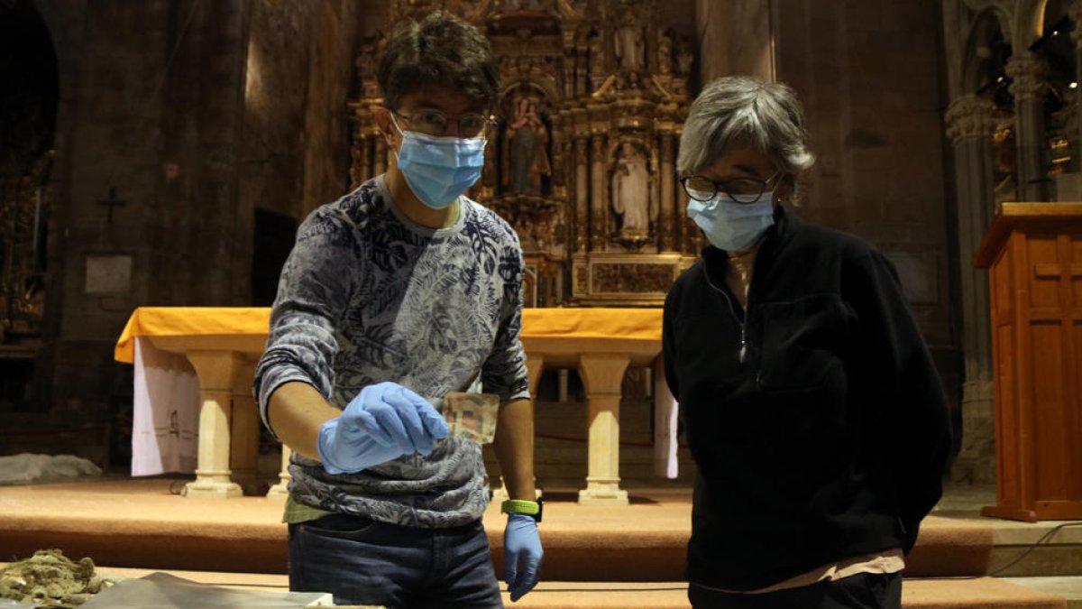 Plano medio del responsable del monasterio de Santes Creus, Joan Ibarz, mostrando uno de los fragmentos de naipes localizados, cerca de la arqueóloga Carme Subiranas.