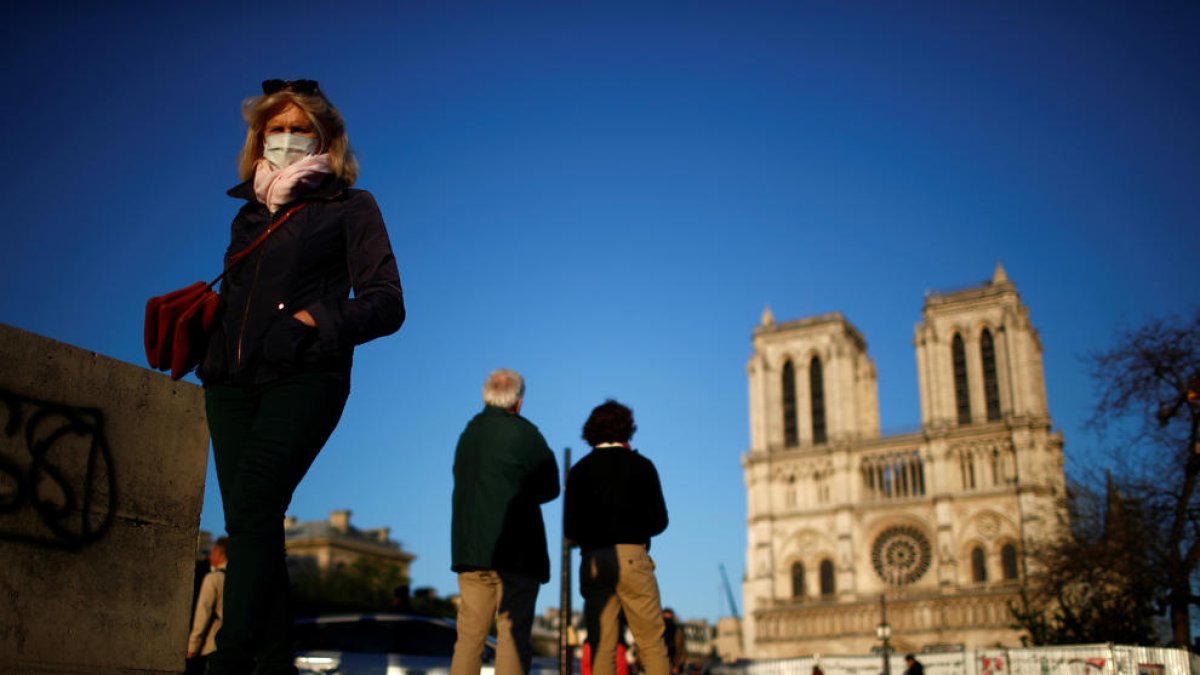 La gente con mascarillas delante de la catedral de Notre-Dame de Paris durante la pandemia del coronavirus.