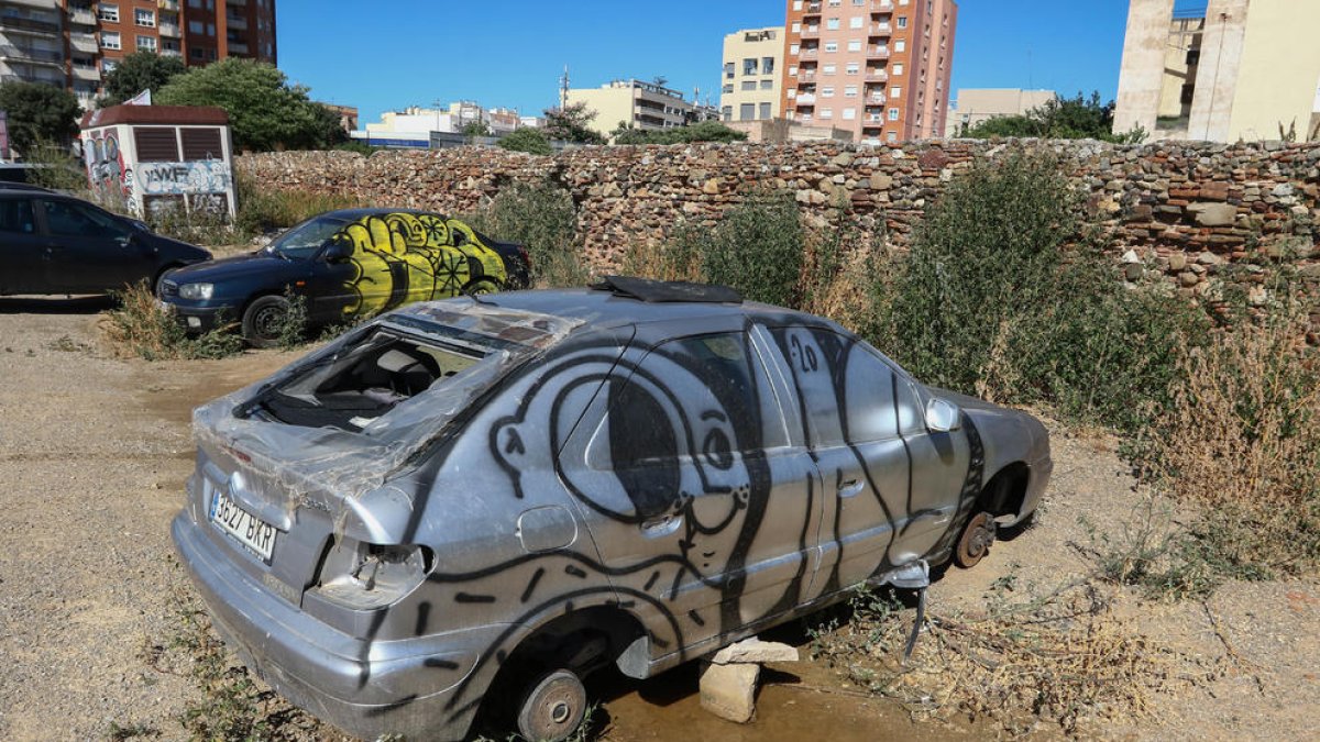 Alguns turismes que semblen abandonats s'aguanten sobre pedres i estan coberts de pintades