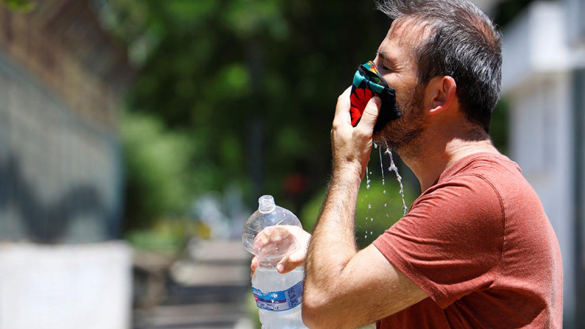 Un home remullant la mascareta per afrontar les altes temperatures.