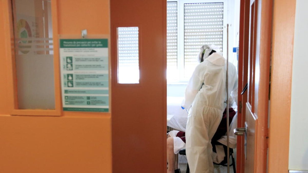 Una profesional sanitaria al lado de un paciente con covid-19 que habla con su familia a través de una tableta en el Hospital del Mar.