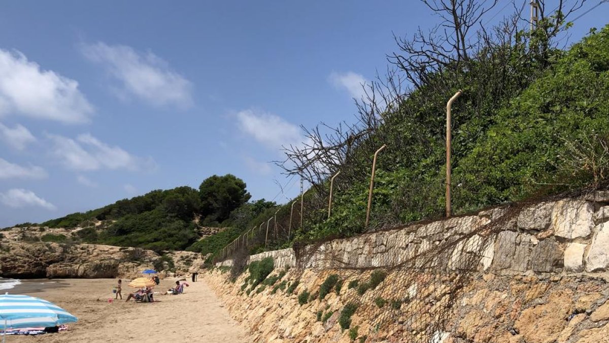 Imagen del mal estado en que se encuentra la valla que separa la vía del tren de la playa Llarga, más estrecha por las crecidas del mar.