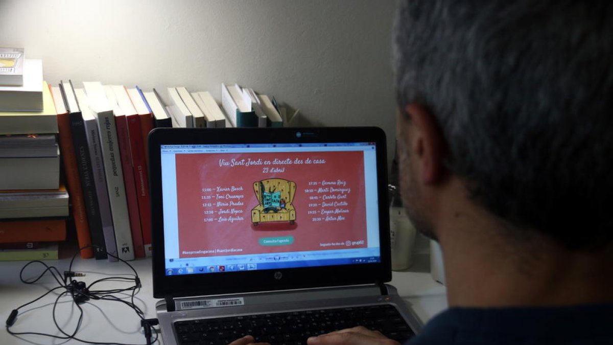 Una persona observa las propuestas online de los autores del Grupo 62 por Sant Jordi.