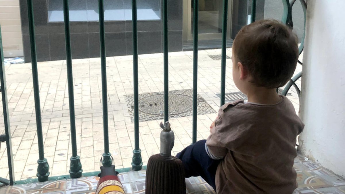 Un nen mira des del balcó de casa, durant el confinament.