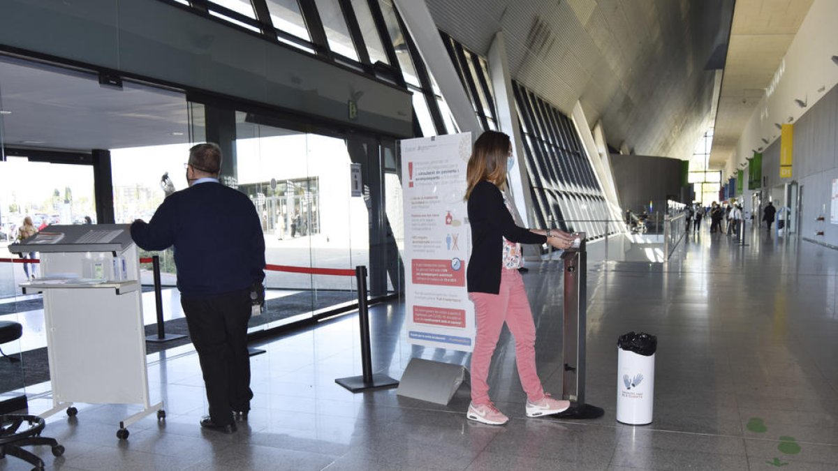 Visitants accedint a l'Hospital de Reus, posant-se gel hidroalcohòlic a les mans, a la porta d'entrada.