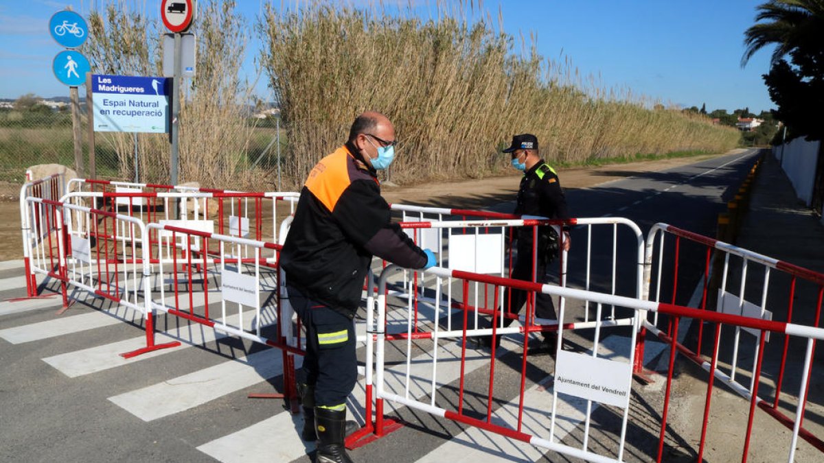 Efectivos de Protección Civil y de la Policía Local del Vendrell acabando de colocar las vallas en un acceso secundario, en torno a las Madrigueres.