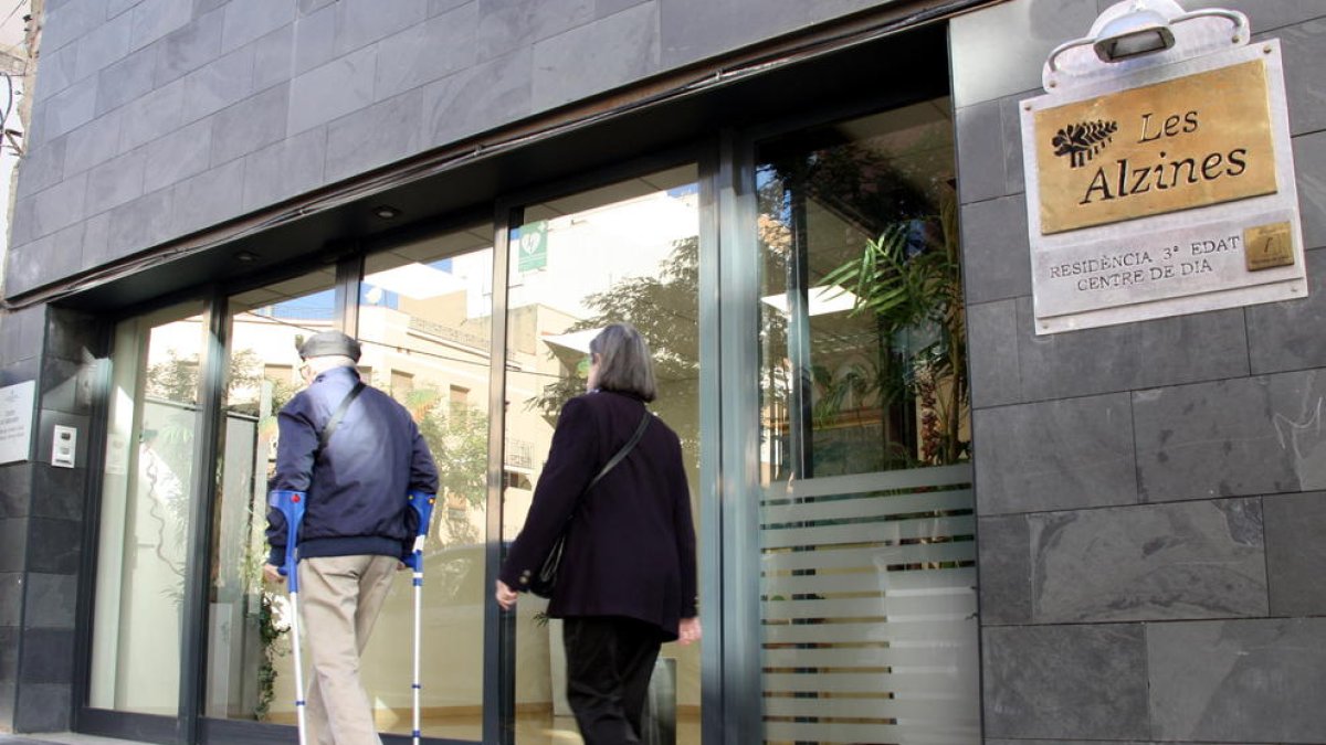 Fachada principal de la residencia Les Alzines de Tarragona, y de una pareja de abuelos a punto de entrar