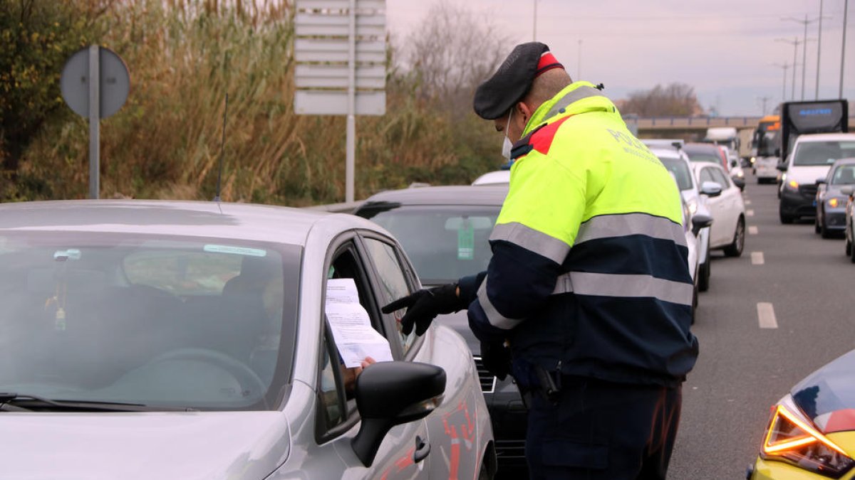 Un agente de los Mossos d'Esquadra comprobando el certificado que le muestra un conductor en un control de tráfico en la T-11, en Tarragona.