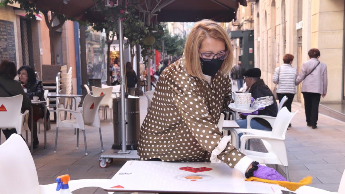 Primer pla d'una restauradora netejant una taula al carrer August de Tarragona.