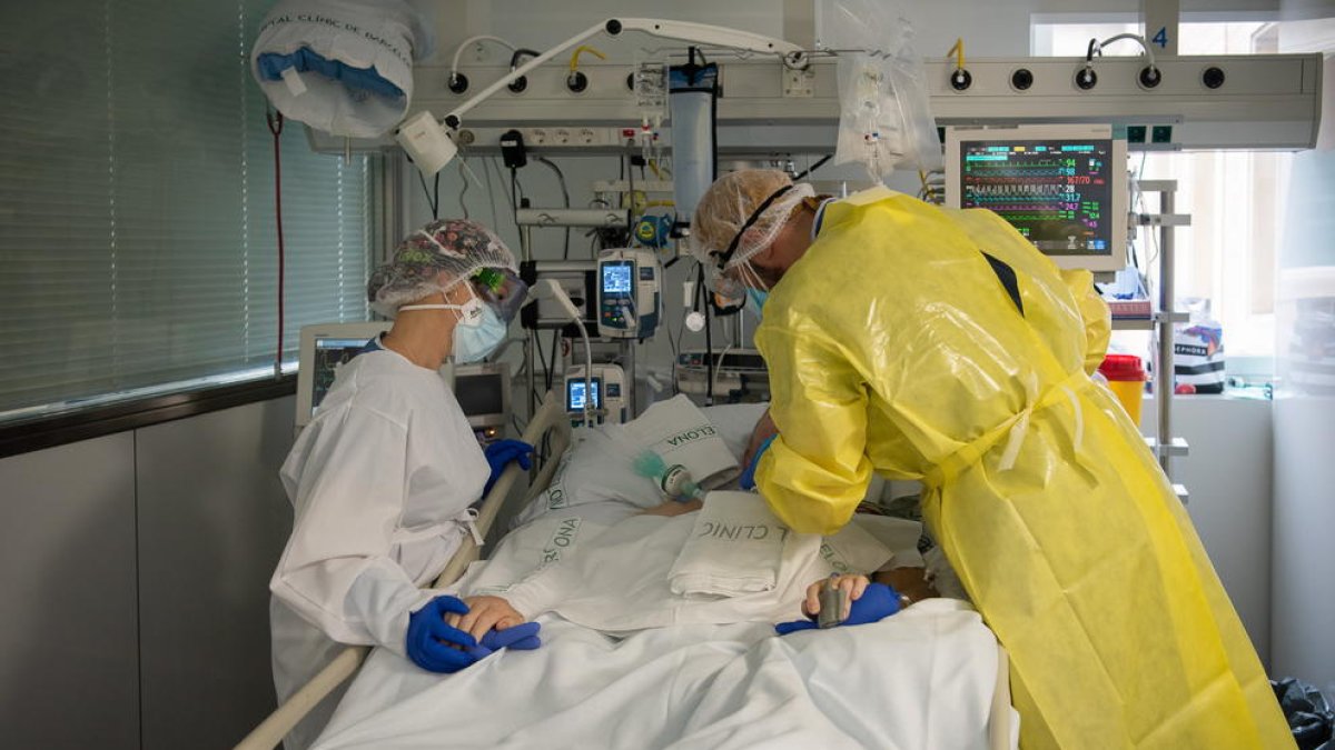 Dos sanitarios visitando a un paciente de covid en el UCI.