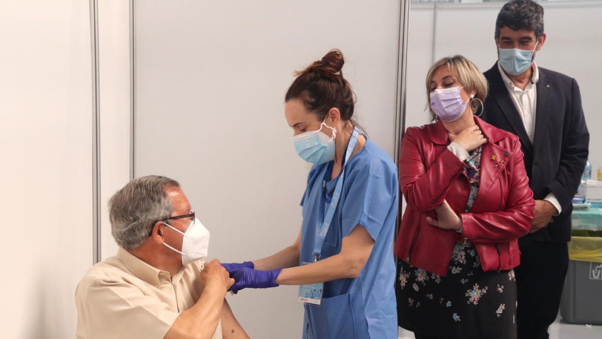 La consellera de Salut, Alba Vergés, mirando como administran una vacuna a un hombre al punto de vacunación masiva del Palau d'Esports Catalunya de Tarragona.