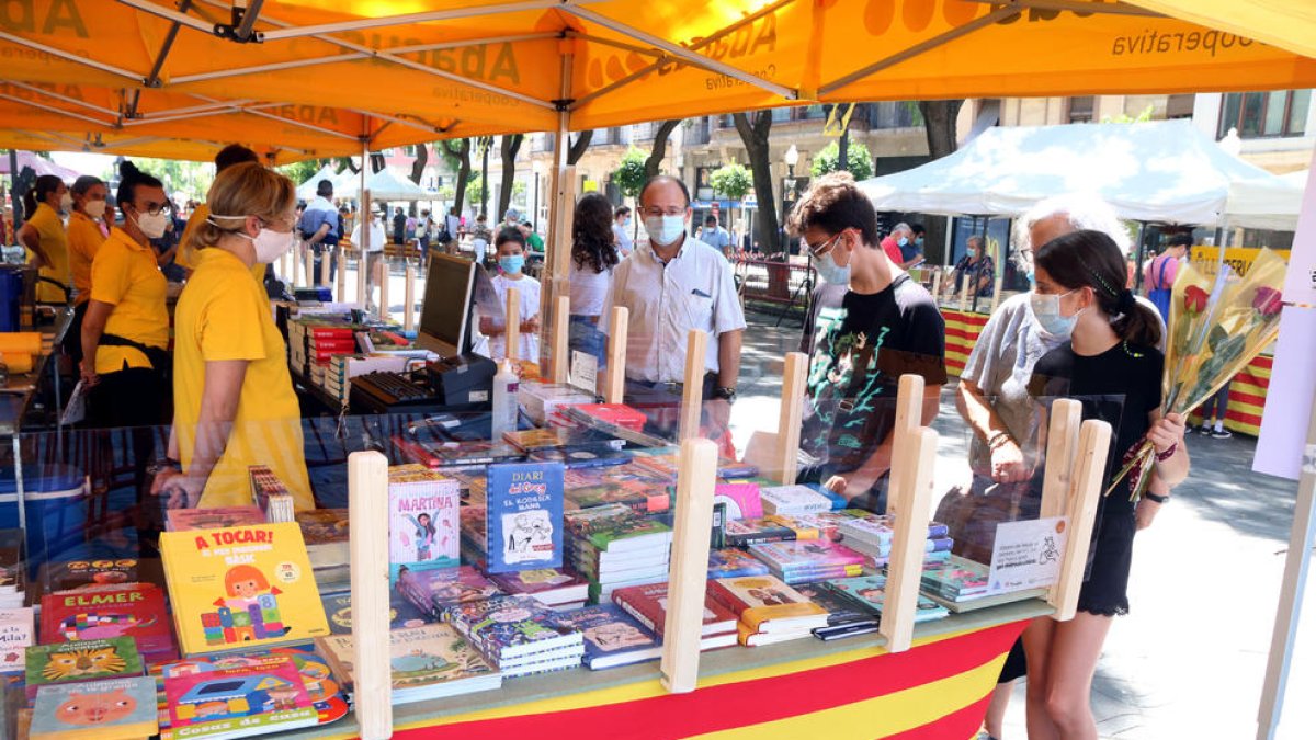 Una puesto de libros en la Rambla Nova de Tarragona con varios clientes.