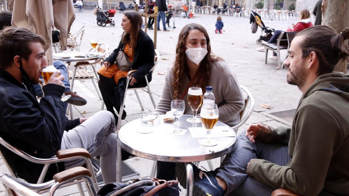 Uns joves prenen una cervesa en una terrassa a la plaça de la Virreina.