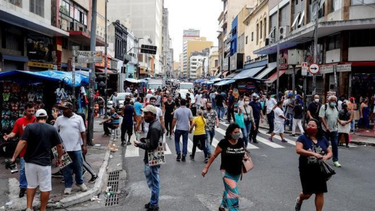 Decenas de personas caminan en una concurrida vía comercial en el centro de Sao Paulo (Brasil).