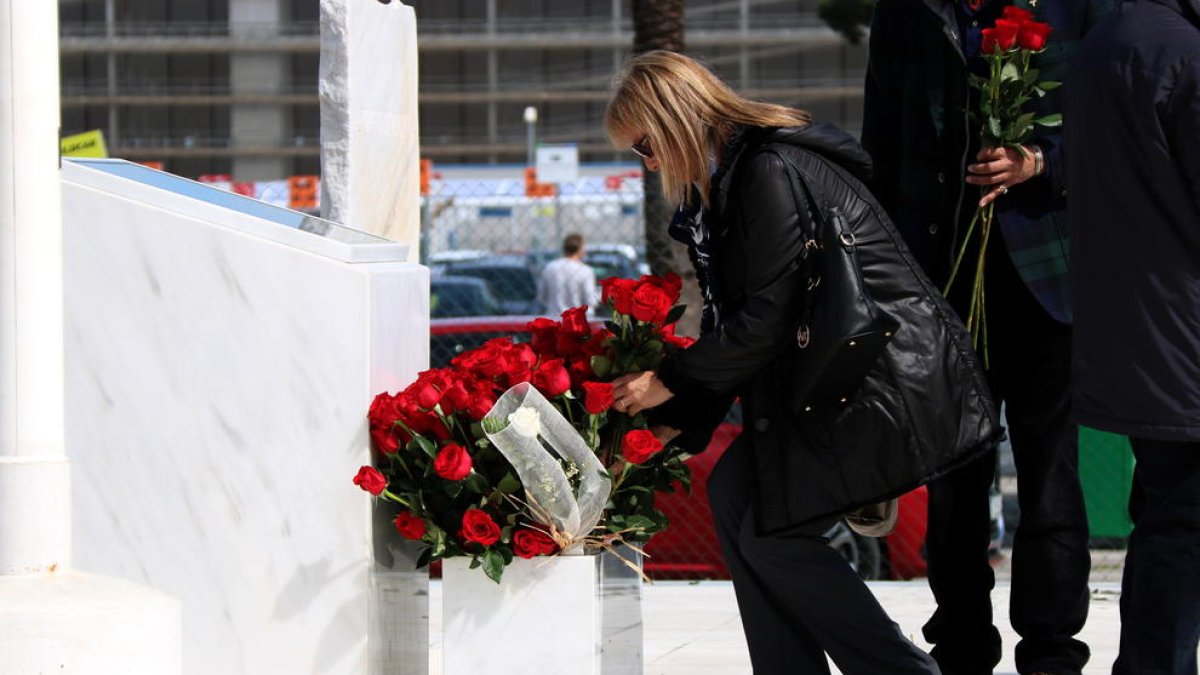 Una afectada per la tragèdia de Germanwings deixant una rosa al monument de la T2 del Prat, durant l'acte d'homenatge a les víctimes en el segon aniversari del succés.