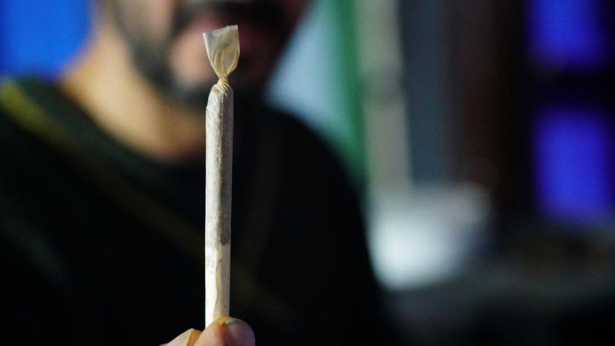 Un home mostrant un cigarret de cannabis.