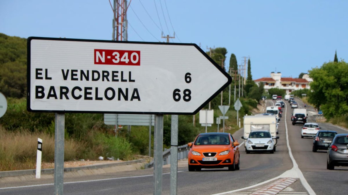 Un letrero de tráfico en primer término a la N-340 en Roda de Berà, con los kilómetros que separan Roda de Berà del Vendrell y Barcelona.