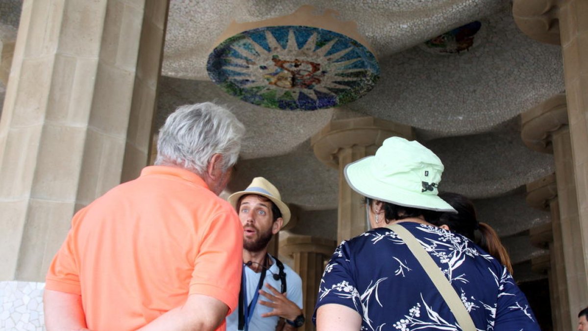 Un guía turístico dando explicaciones a un grupo de personas en la sala Hipóstila del Parc Güell.