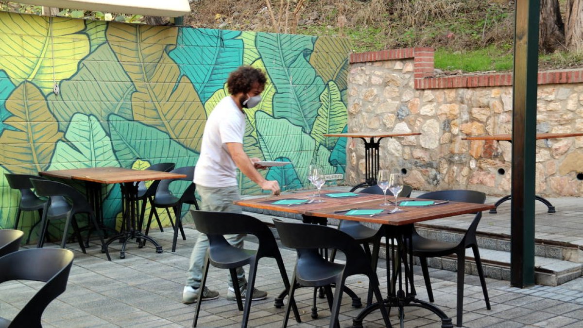 Plano general del copropietario del restaurante Botànic de Tortosa poniendo mesas en la terraza del establecimiento antes de la reapertura del mediodía.