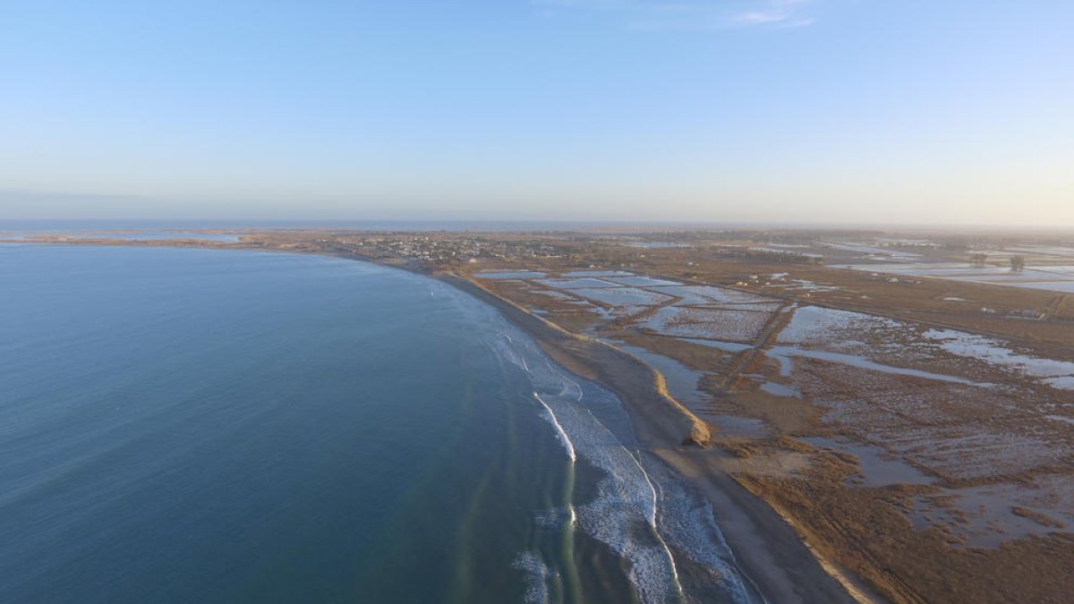 Pla aeri de la platja de la bassa de l'Arena, amb el cordó dunar interromput en alguns punts i la urbanització de Riumar al fons.