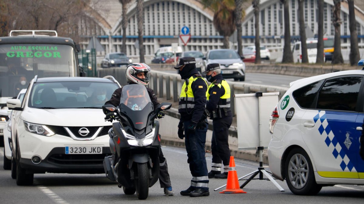 La Guardia Urbana de Barcelona habla con un motorista durante un control en la Ronda Litoral a raíz del confinamiento municipal.